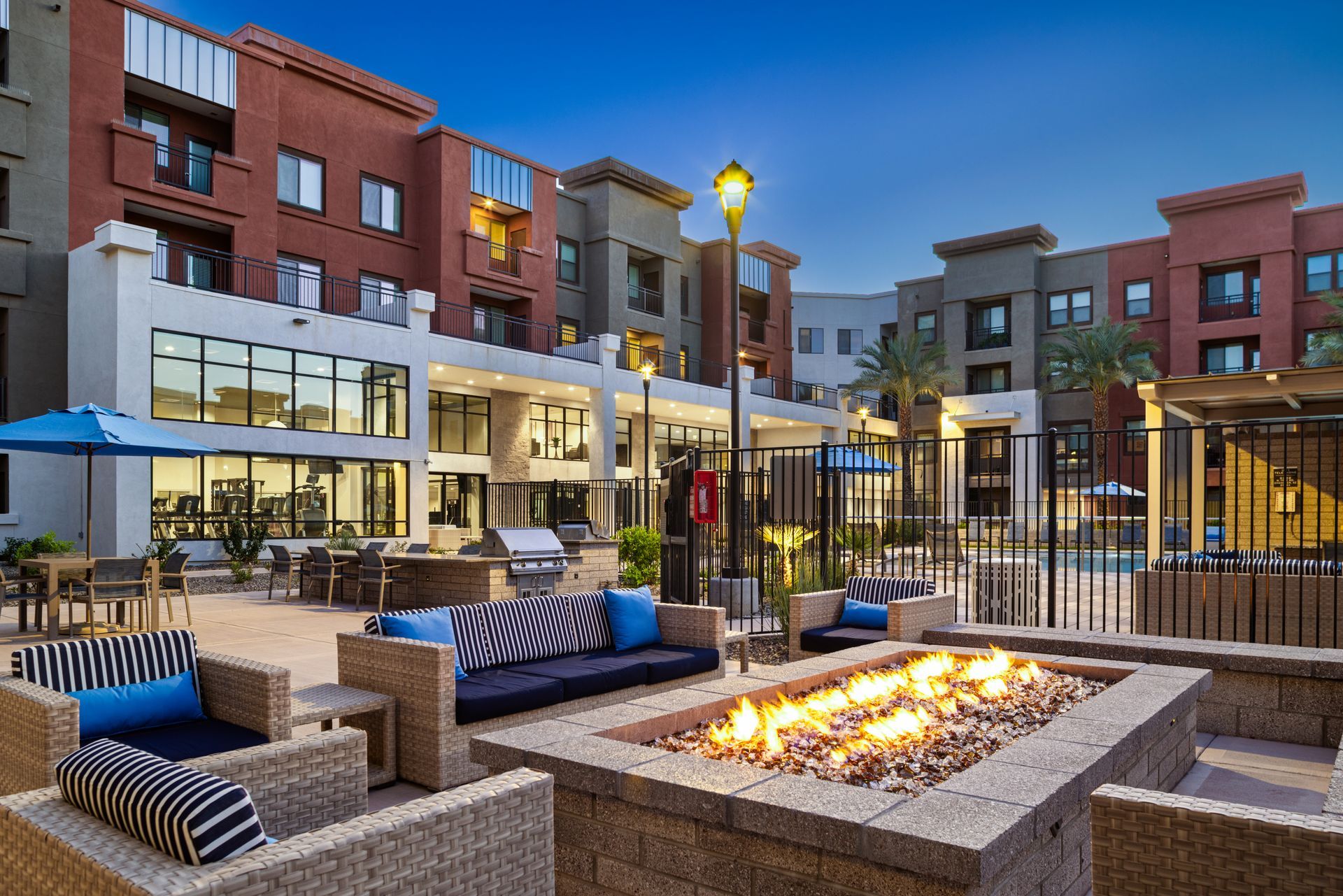 Modern apartment courtyard with outdoor seating and a lit fire pit at dusk