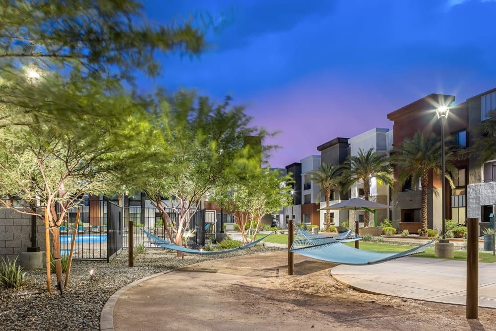 Courtyard with trees, pathways, and modern apartment buildings at dusk