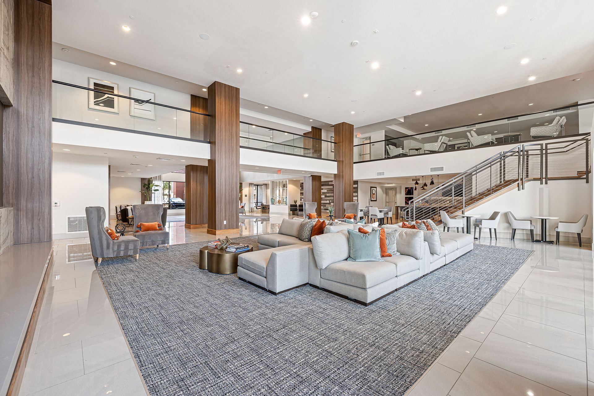 Modern lobby with gray sectional, tall windows, and staircase