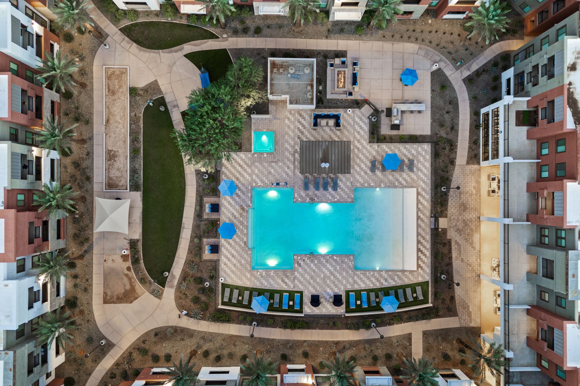 Aerial view of a resort courtyard with a large turquoise swimming pool and surrounding apartment buildings.