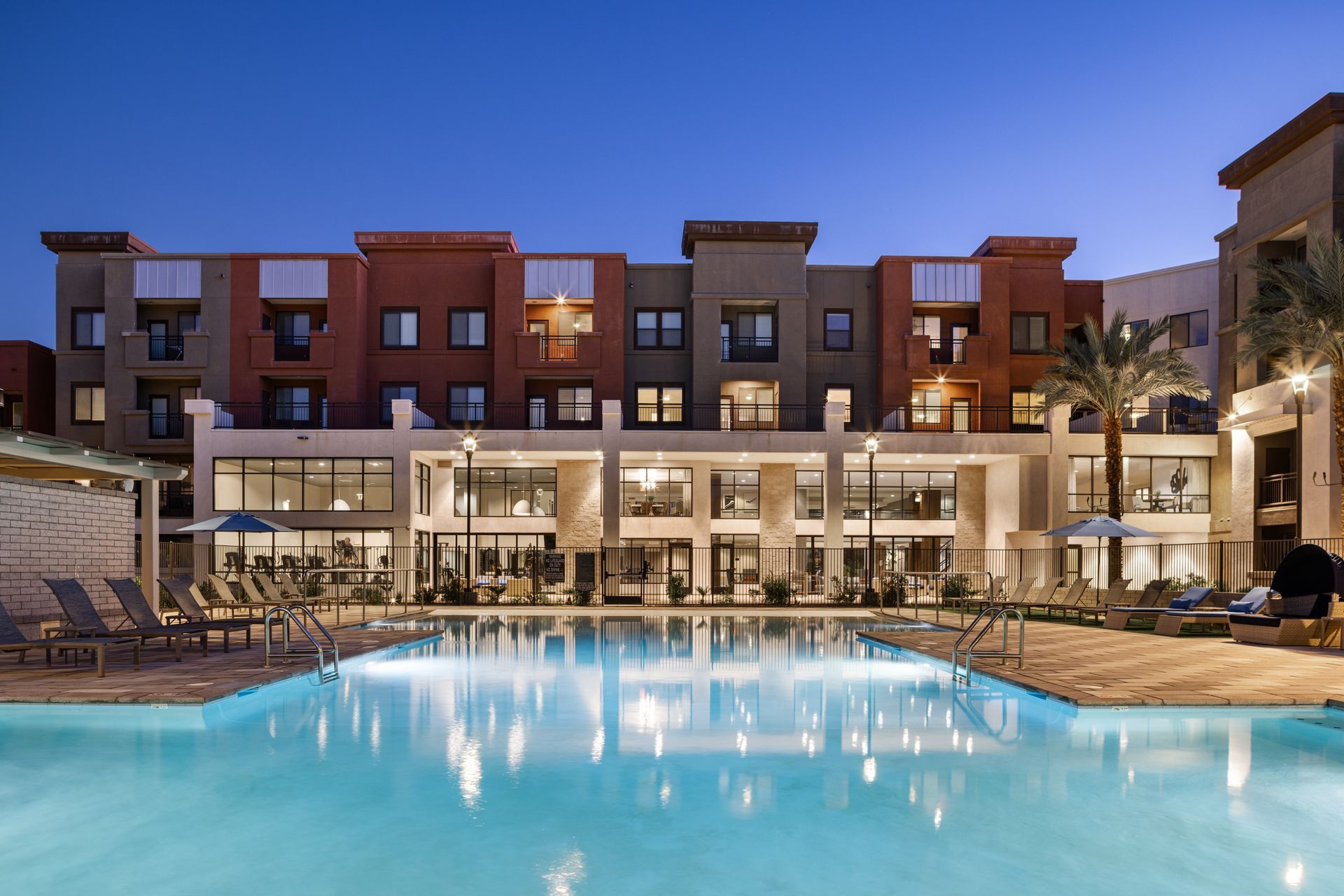 Modern apartment courtyard with illuminated pool at dusk