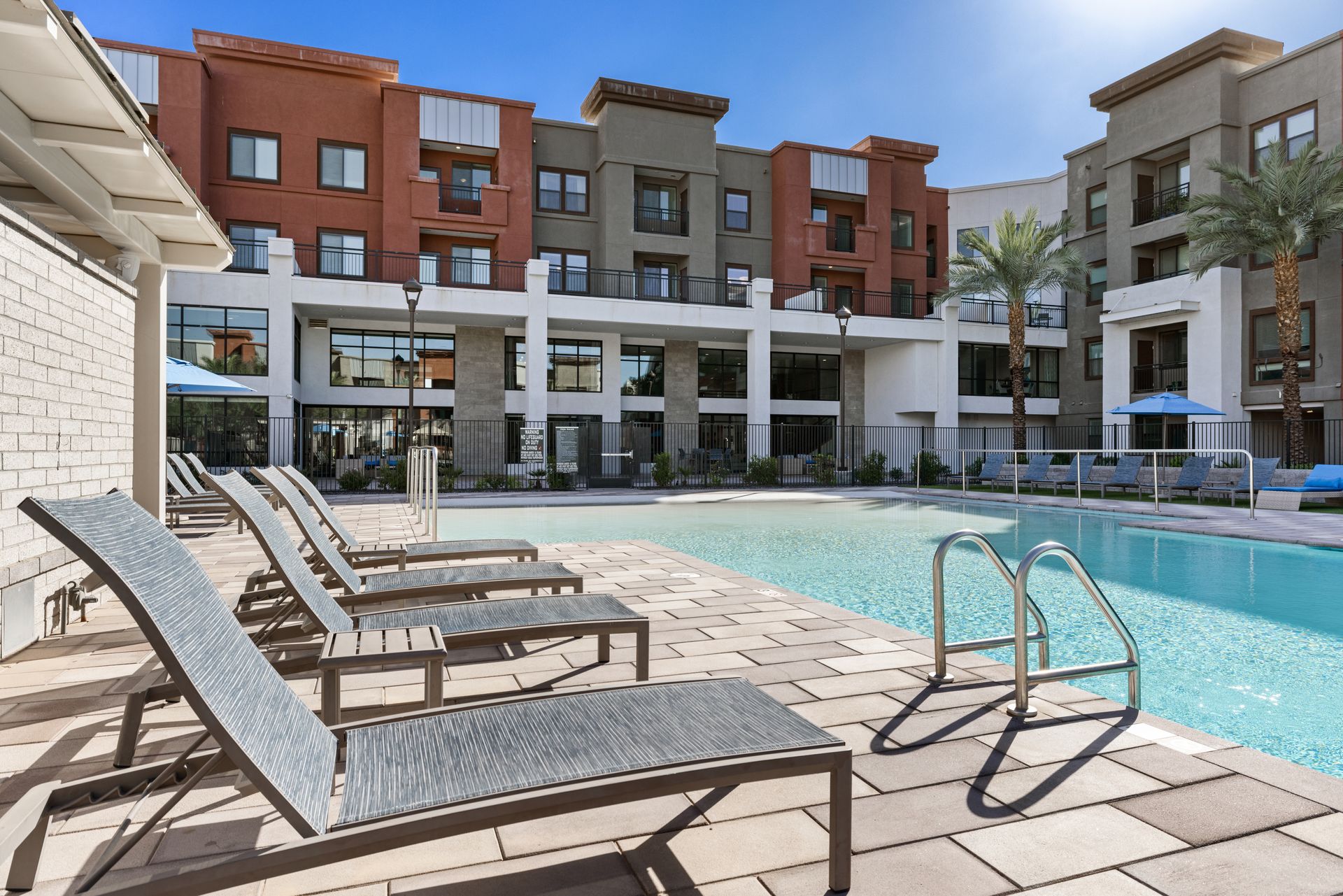 Rooftop pool with lounge chairs and modern apartment buildings in the background