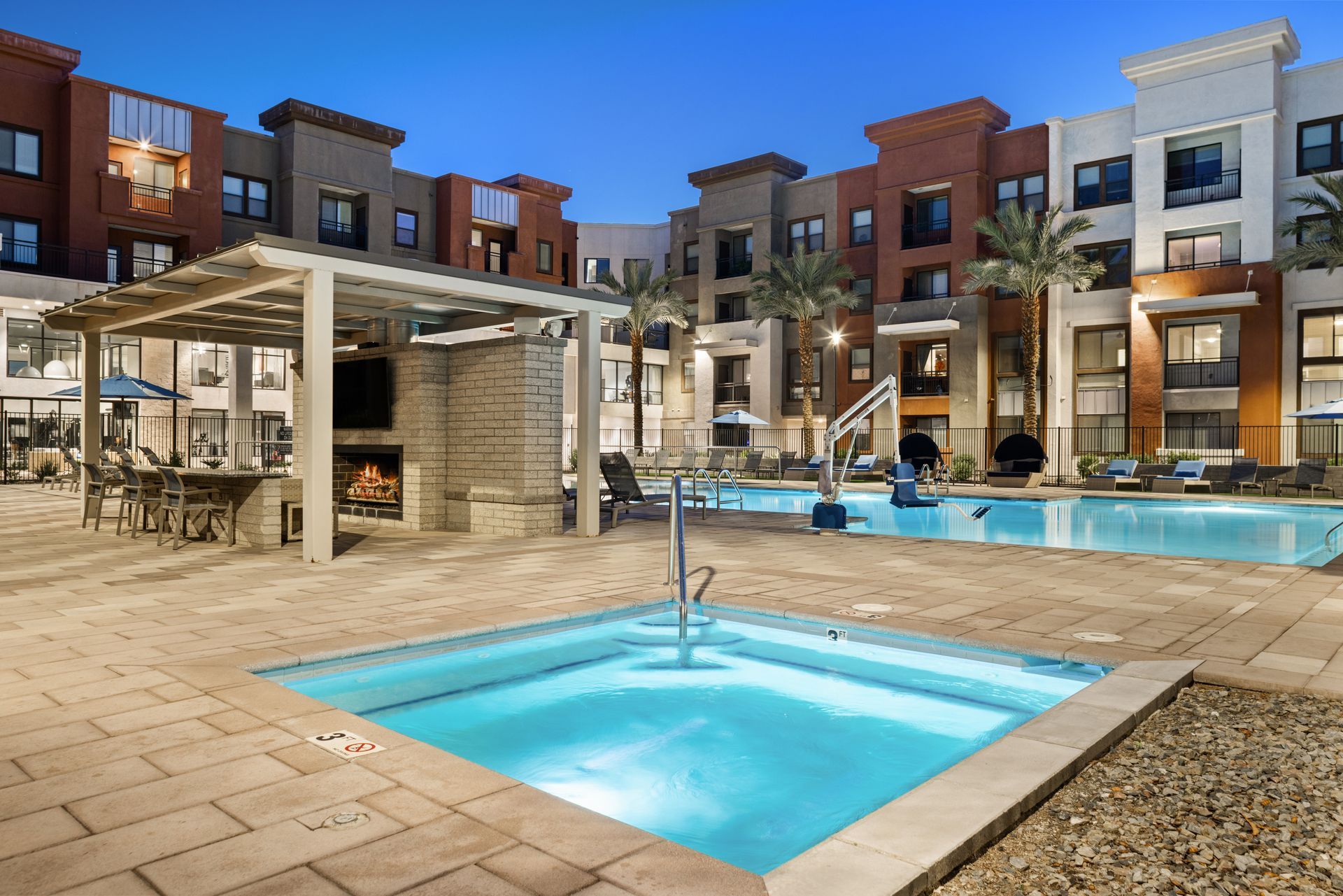 Modern apartment courtyard with pool and hot tubs at dusk