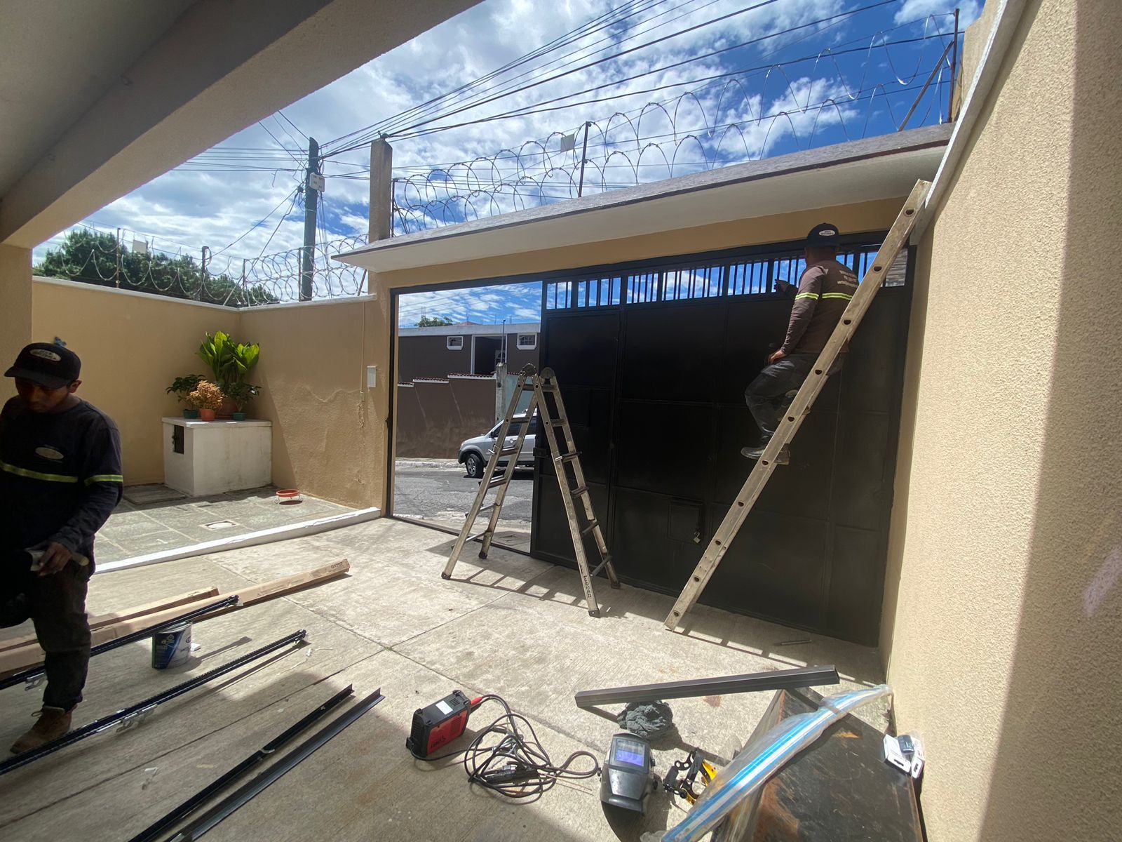 Técnicos instalando motor y sistema de seguridad en portón automático residencial