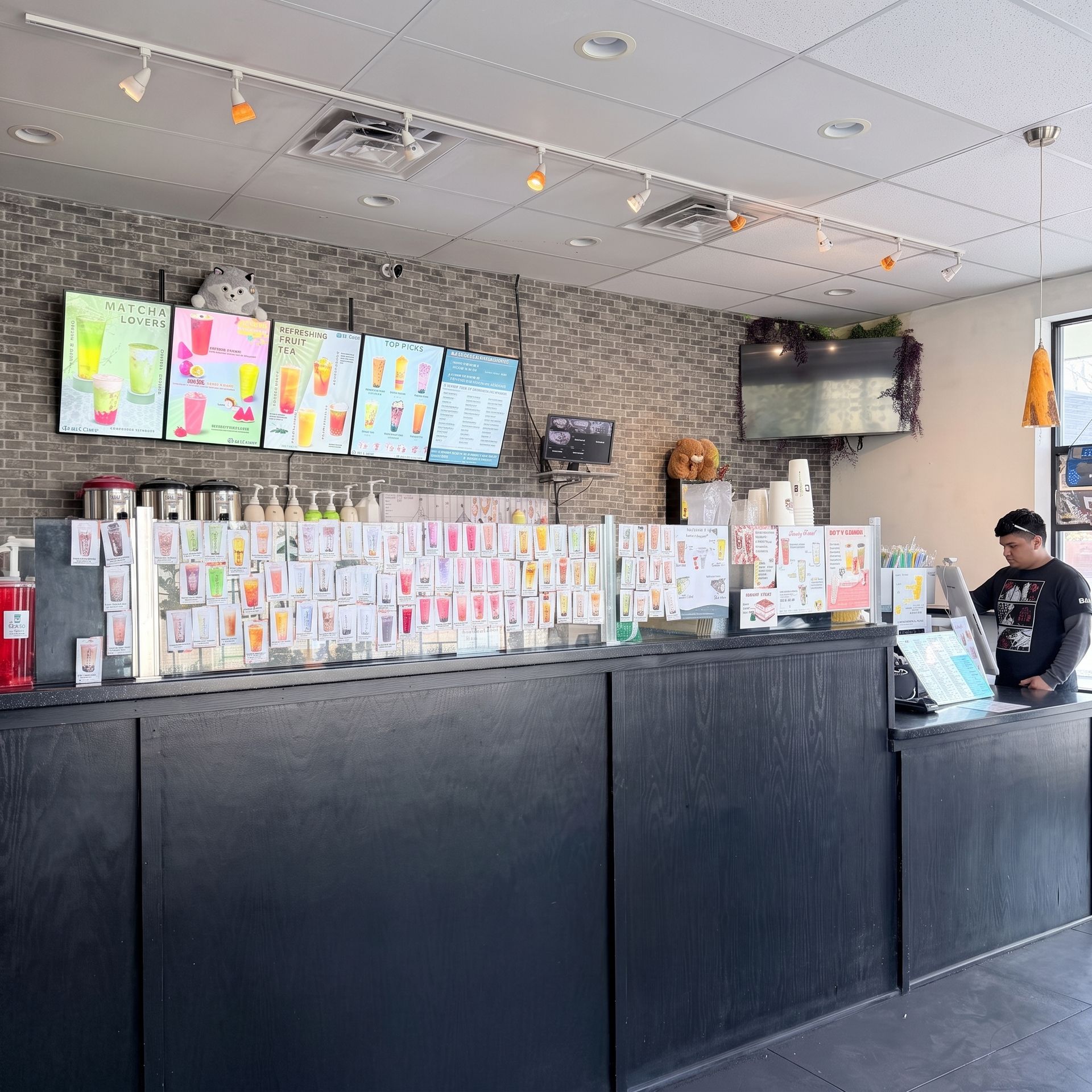 Retail counter covered with colorful cards and notes, with a staff member standing behind it in a bright shop