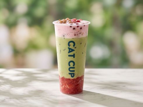 Cat Cup layered green and red dessert drink with pink foam in a clear cup on a table