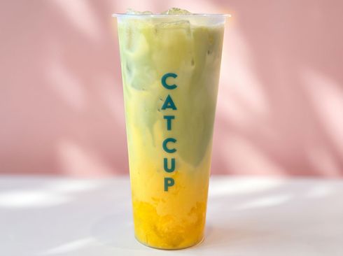 Tall layered drink in a clear cup with vertical “CATCHUP” text, against a pink background