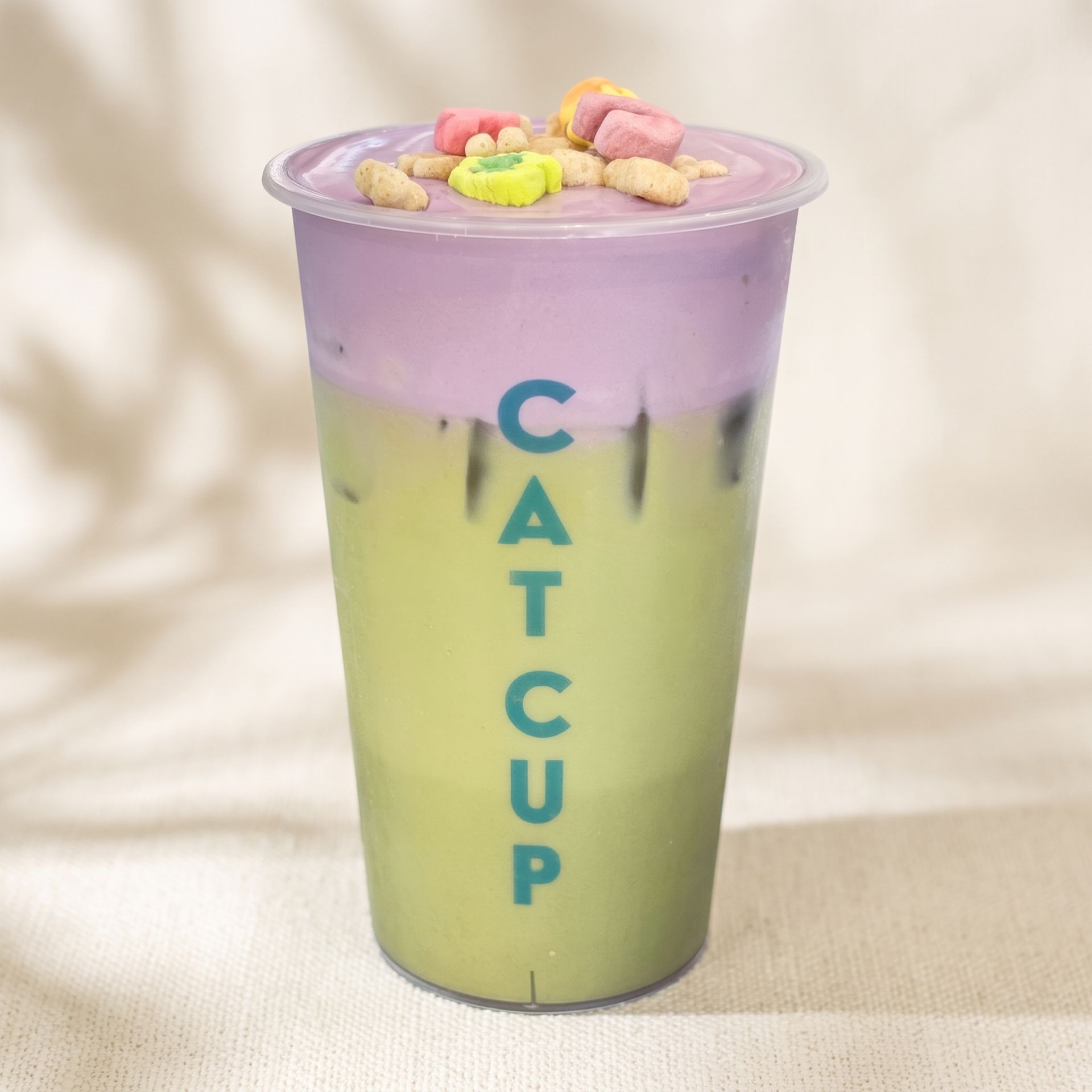 Pastel purple-and-yellow Cat Cup drink with a lid and colorful cereal on top