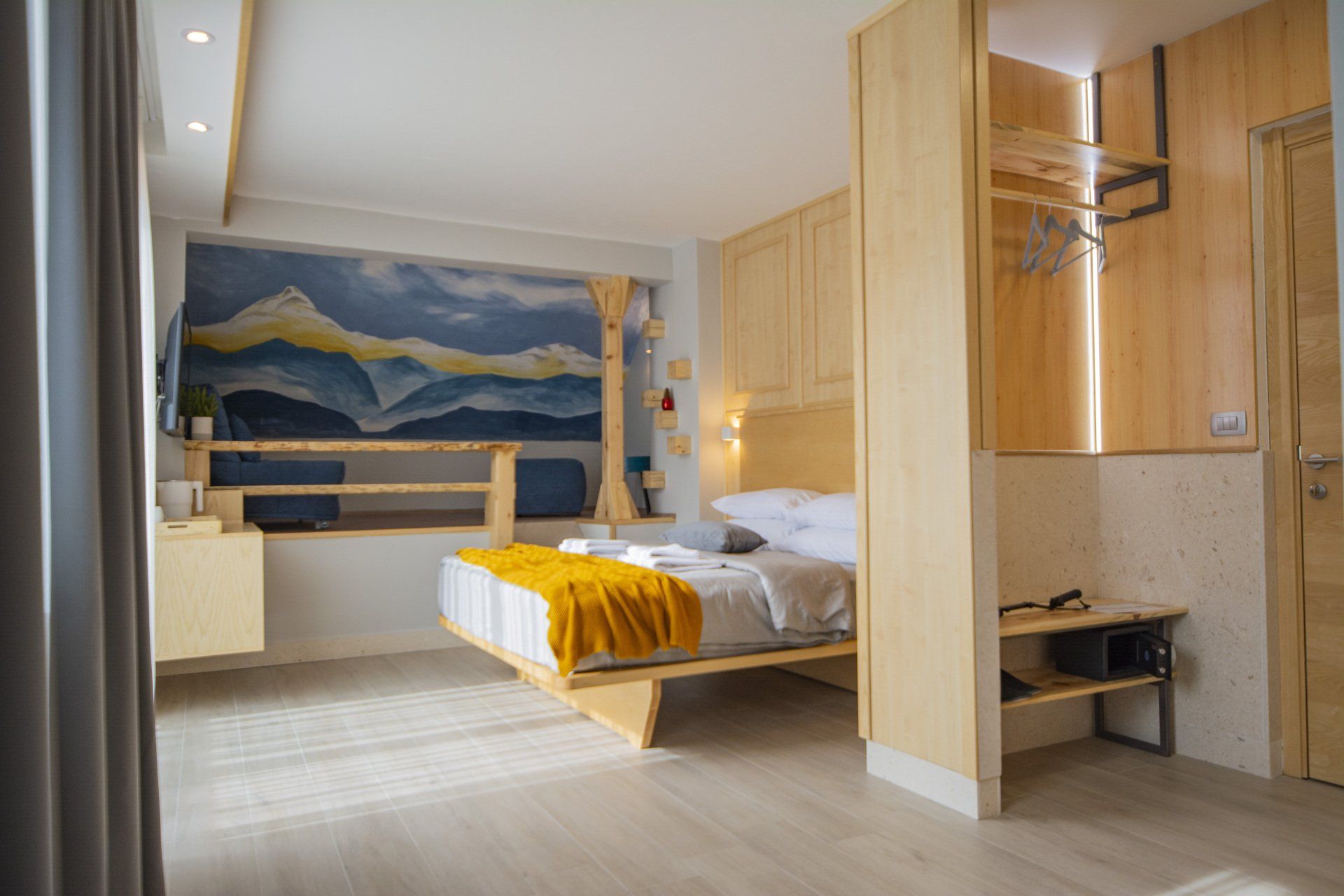 A hotel room with a king size bed and a painting of the mountain on the wall.