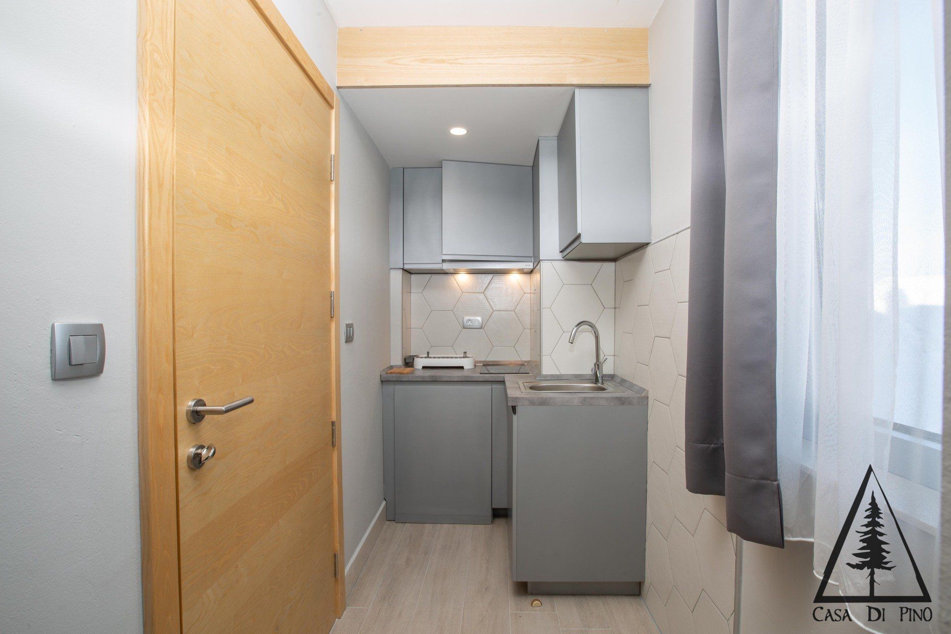 A small kitchen with a sink, cabinets, and a door.