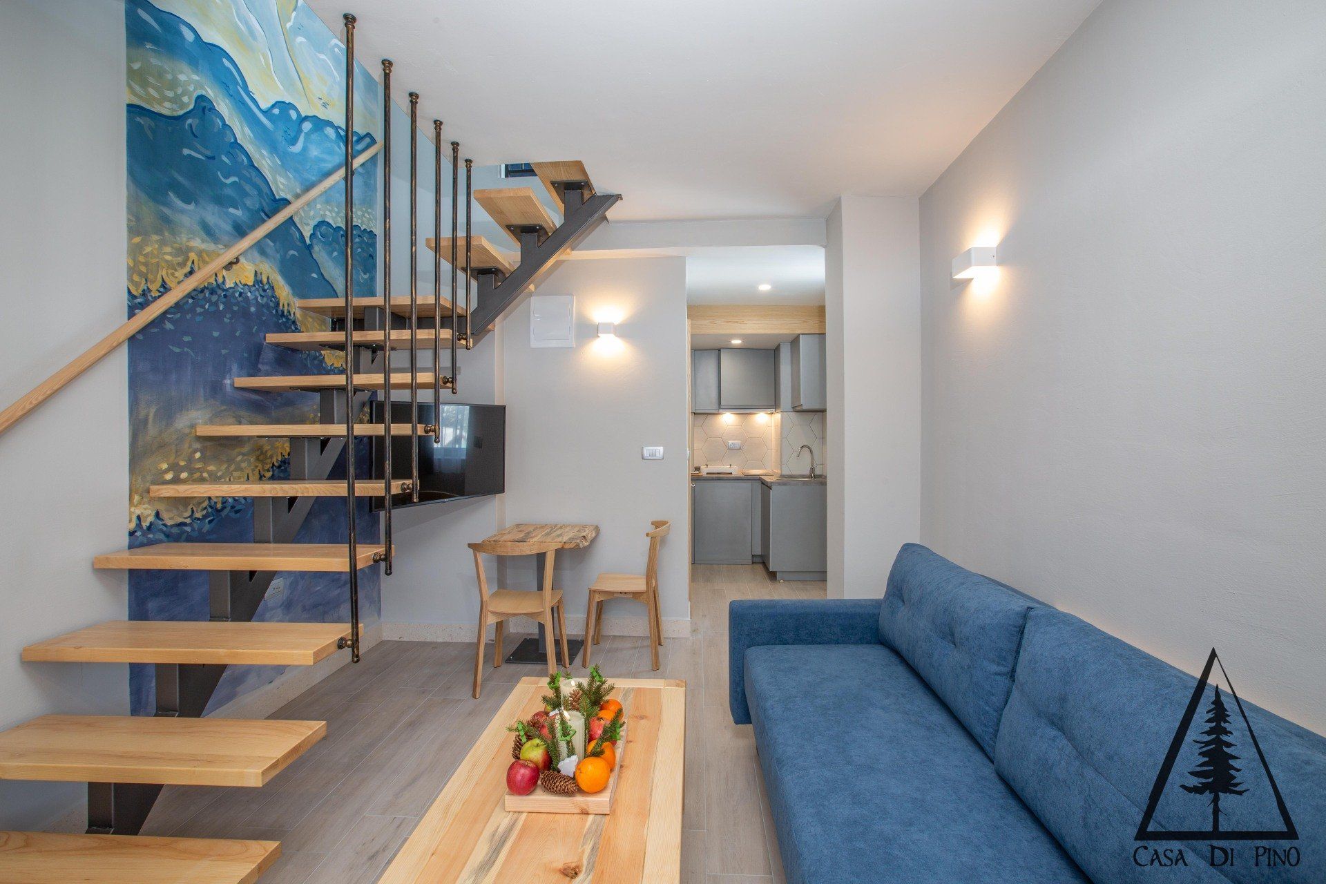 A living room with a blue couch and stairs leading up to the second floor.
