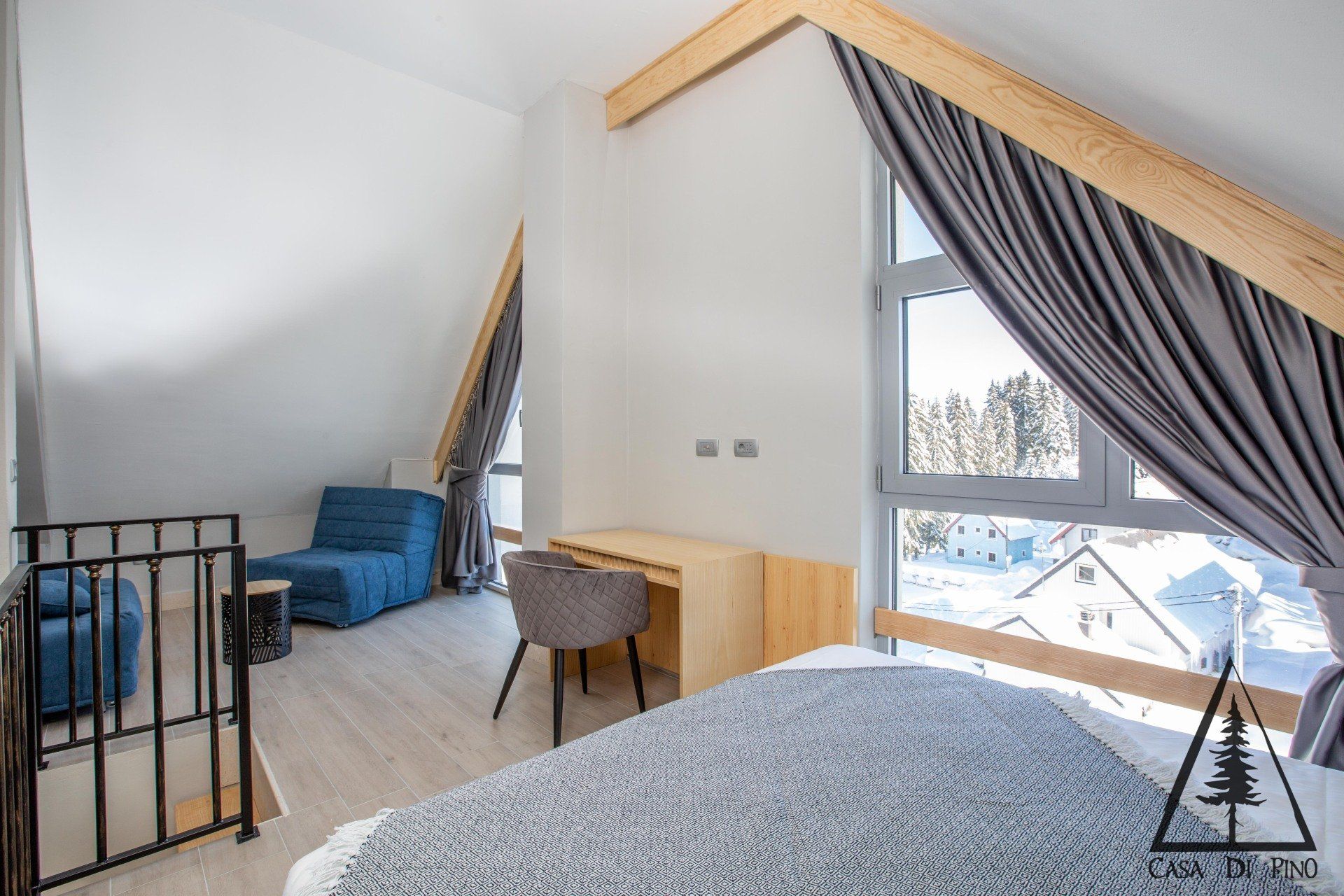 A bedroom with a bed , desk , chair and large window.