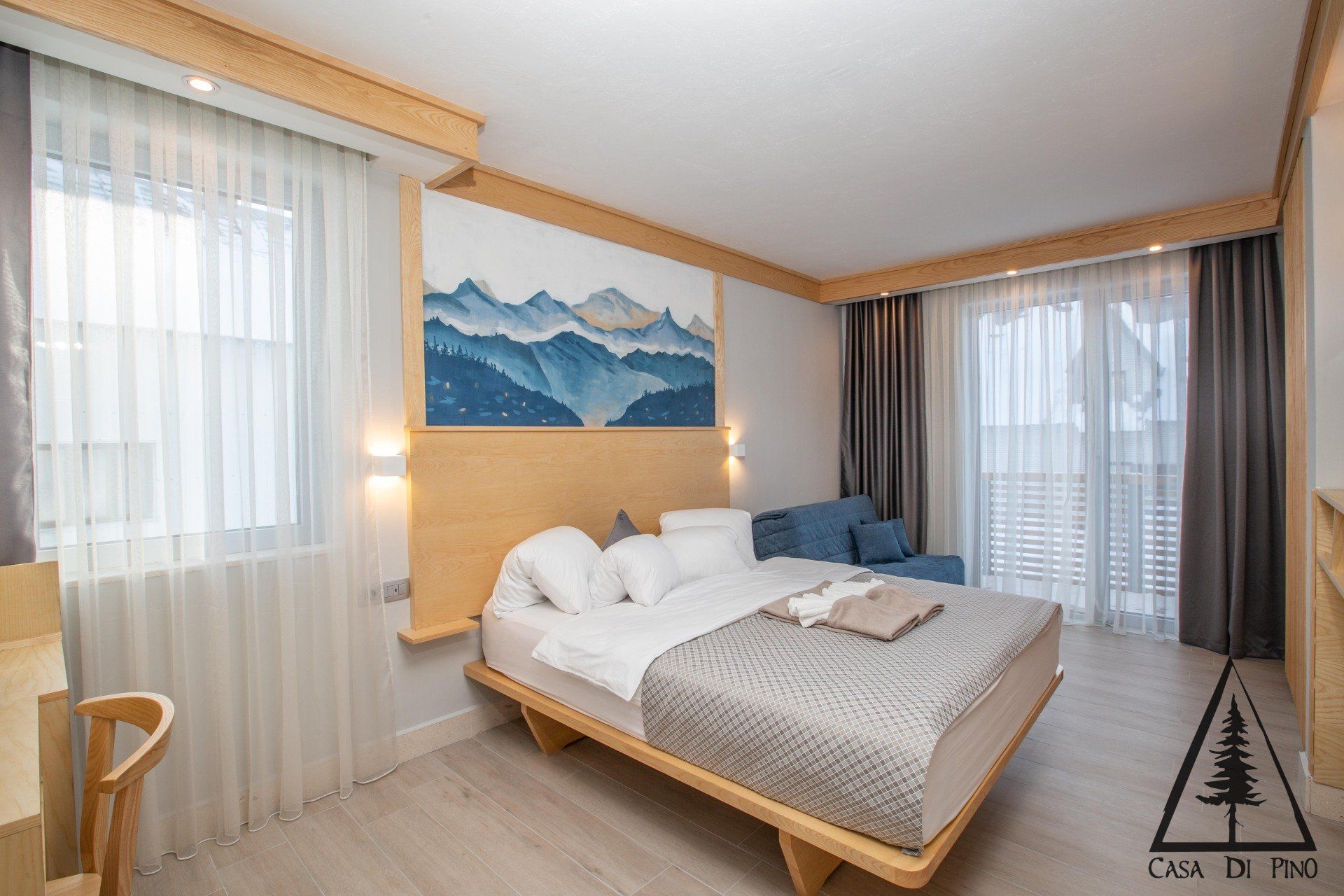 There is a king size bed in the middle of the hotel room and a wall mural above the bed.