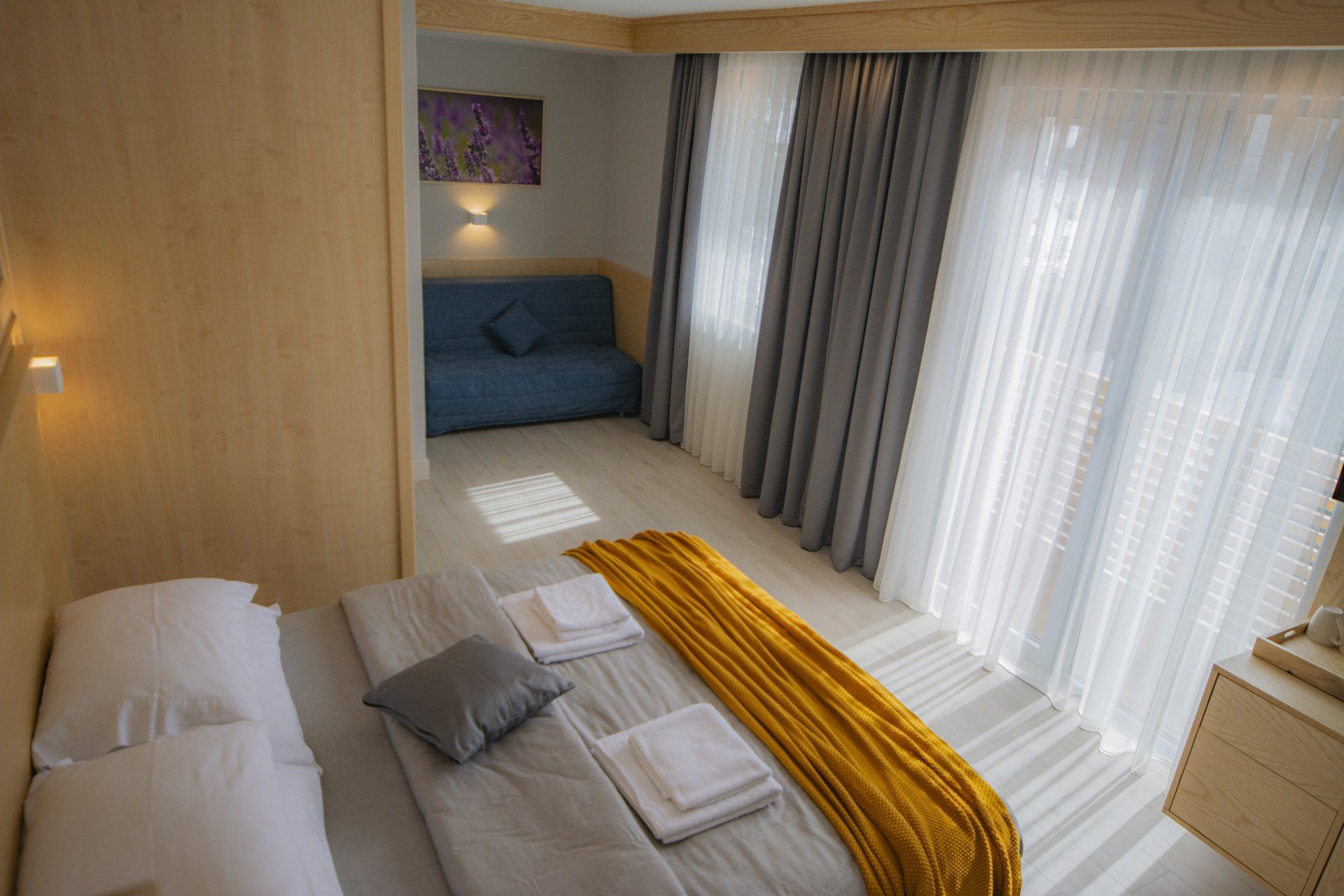 A hotel room with a bed, couch, and curtains.