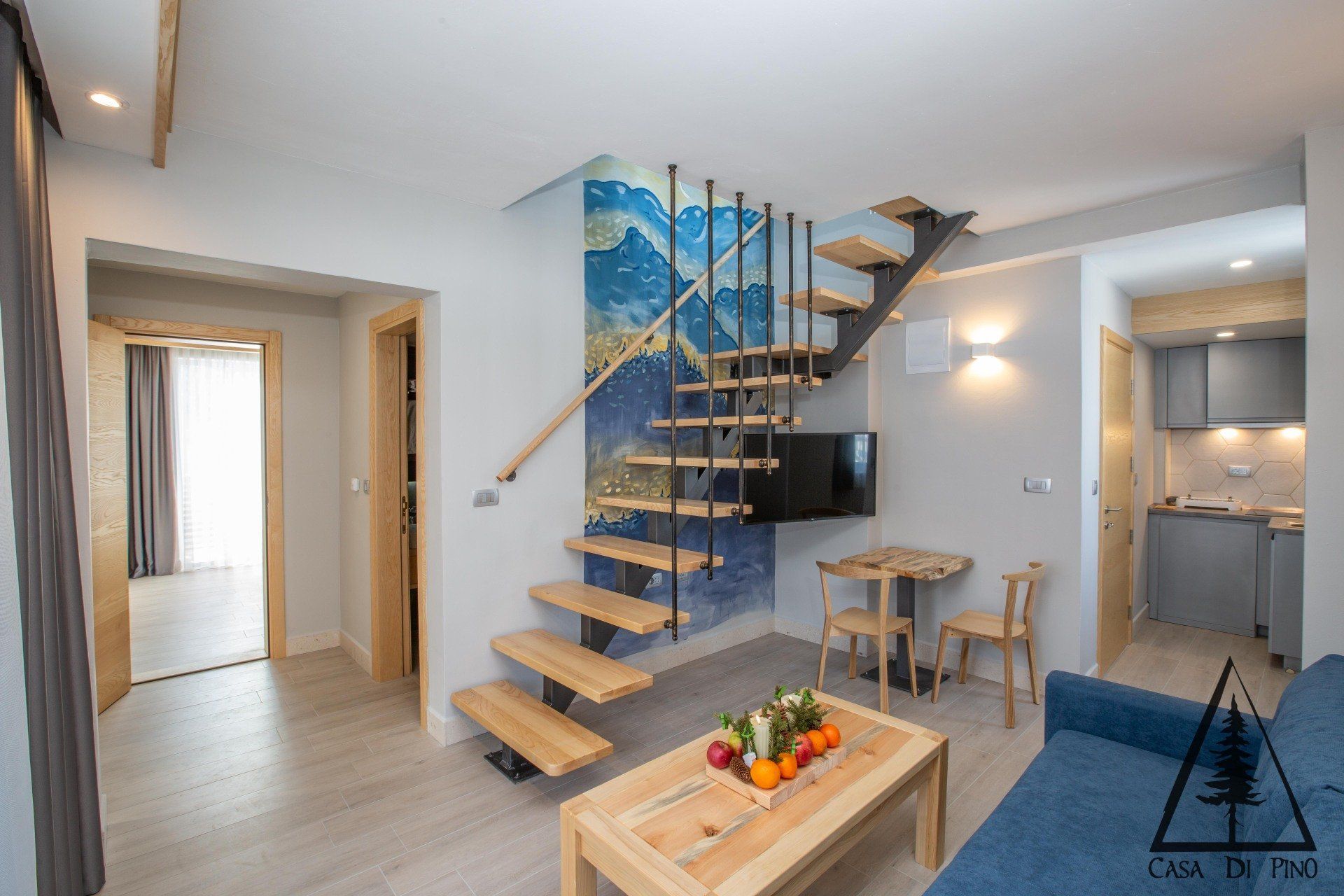A connecting living room in a hotel penthouse with a staircase leading up to the second floor.