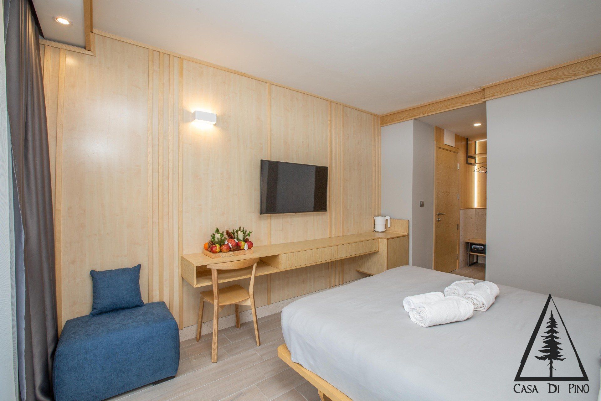 A hotel room with a bed, desk, chair and flat screen tv.