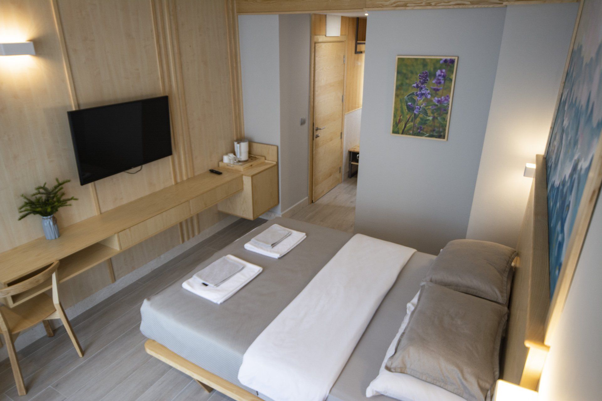 A bedroom with a bed, desk, television and painting peppermint on the wall.