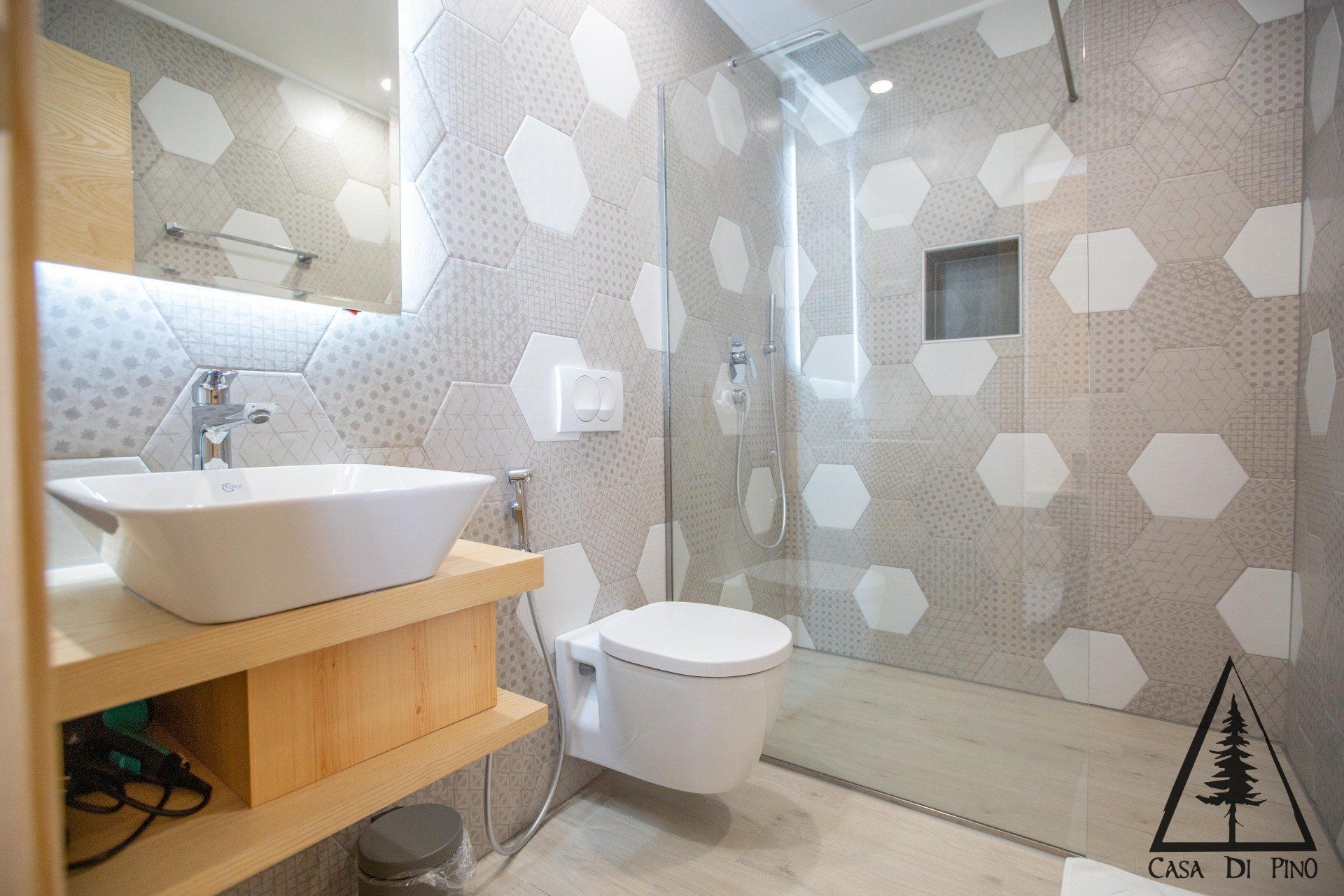 A bathroom with a toilet, sink, mirror and walk in shower.