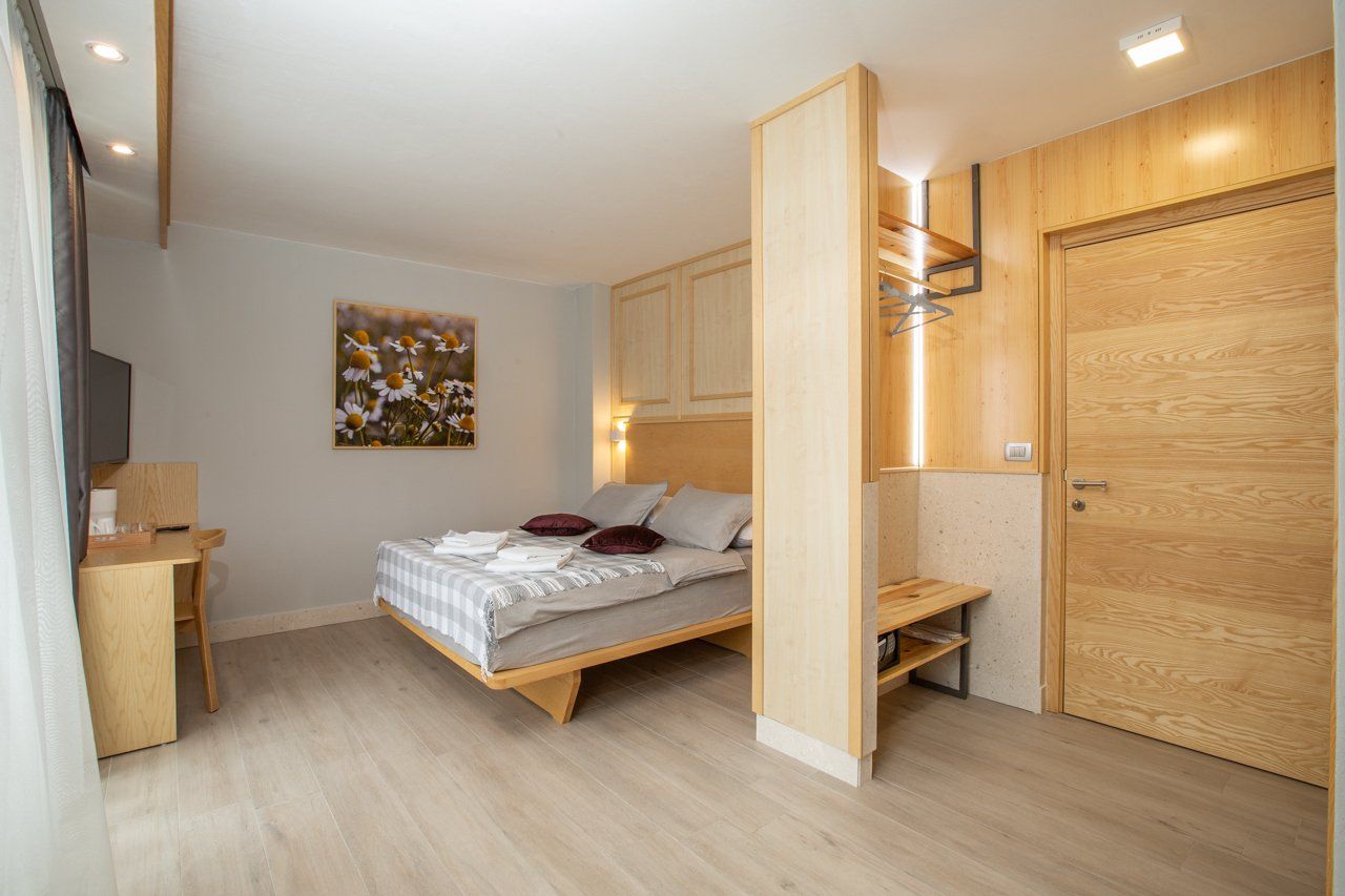 A hotel room with a large bed and a wooden door and shelf.