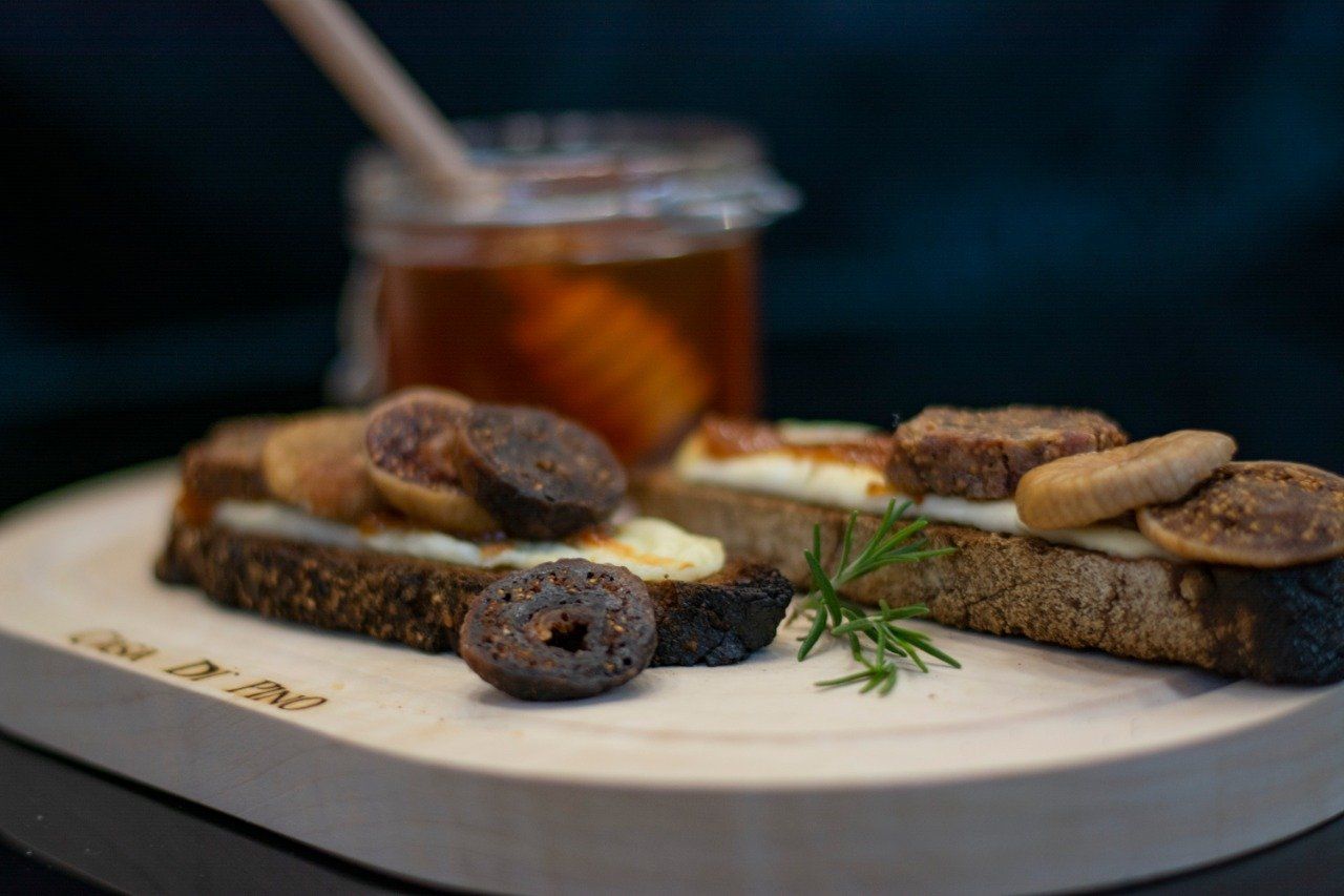 A wooden cutting board topped with sandwiches and a jar of honey.