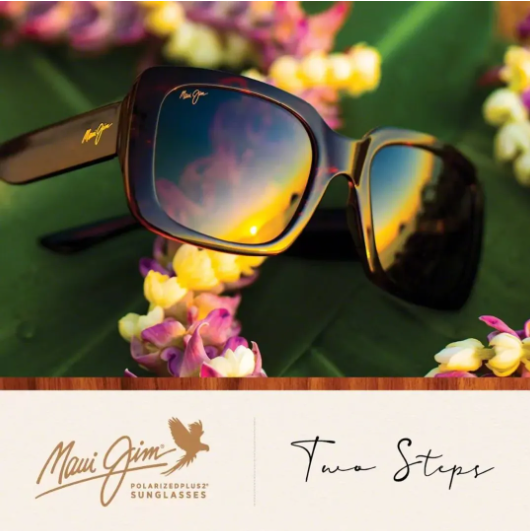 Maui Jim sunglasses with sunset reflection, resting among colorful flowers on green leaves