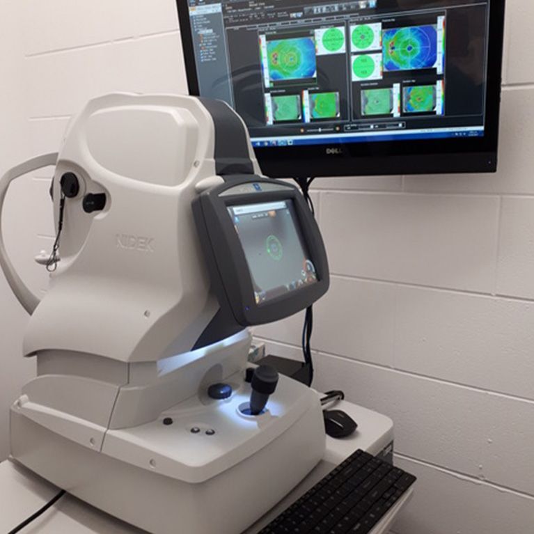 Optical imaging device in a clinic, showing scan results on a wall monitor