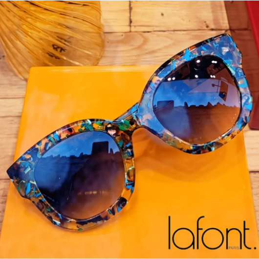 Blue-tinted cat-eye sunglasses with a multicolored frame on an orange surface, Lafont logo visible