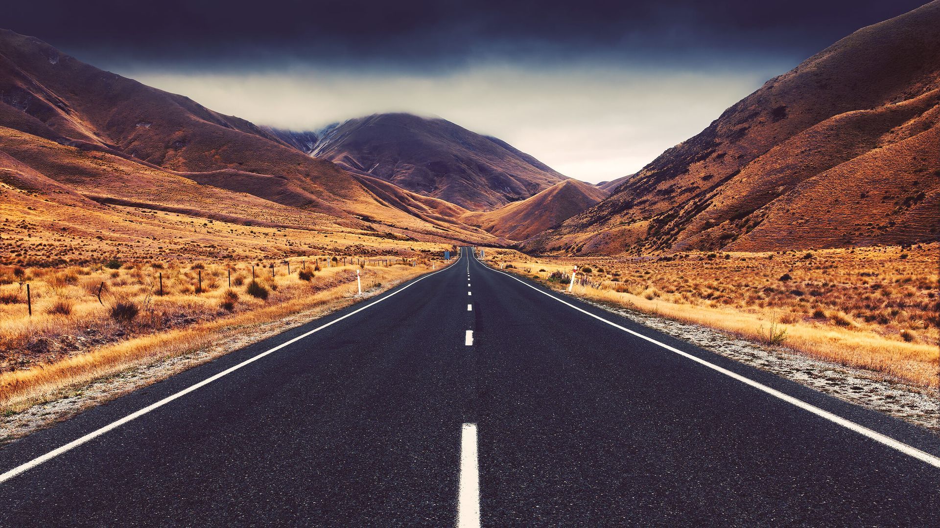 Empty highway through dry mountains under a cloudy sky