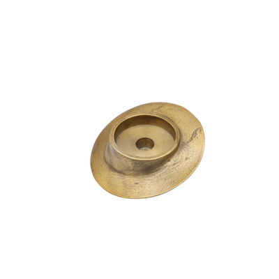Een schuine, ronde messing kaarsenhouder met een gestructureerde, metallic afwerking op een effen witte achtergrond.