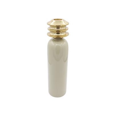 Een beige, cilindrische keramische vaas met een gestapelde, metallic goudkleurige halsdop tegen een witte achtergrond.