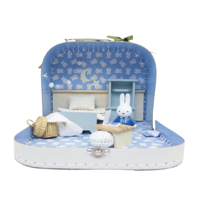 Een klein blauw kofferje met miniatuurslaapkamer met een Miffy-figuurtje, een bed, een bureau en een rieten mand.