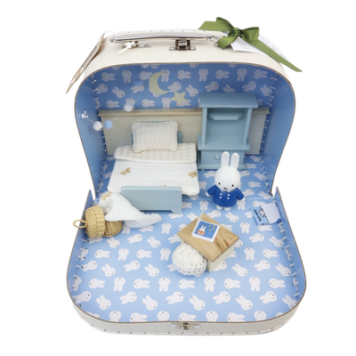 Een klein blauw kofferje met miniatuurslaapkamer met een Miffy-figuurtje, een bed, een bureau en een rieten mand.