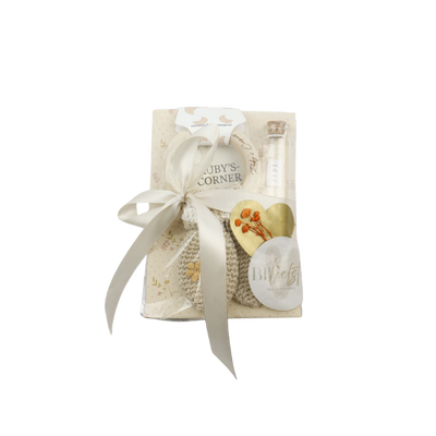 Een cadeauset, bestaande uit een gehaakte rammelaar, een klein glazen flesje en een hartvormig label.