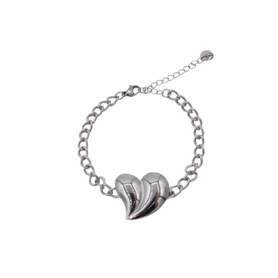 Een gouden schakelarmband met een opvallend, sculpturaal, bolvormig hartvormig bedeltje op een witte achtergrond.