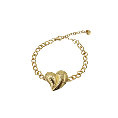Een gouden schakelarmband met een opvallend, sculpturaal, bolvormig hartvormig bedeltje op een witte achtergrond.