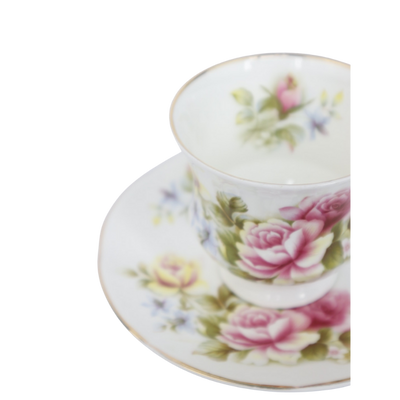 Een wit porseleinen theekopje met schoteltje, versierd met delicate roze rozenbloesems en groene blaadjes.
