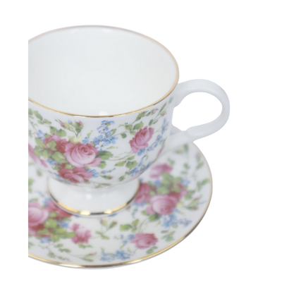 Een wit theekopje met schoteltje, versierd met een patroon van rozen en kleine blauwe bloemen op een effen witte achtergrond.