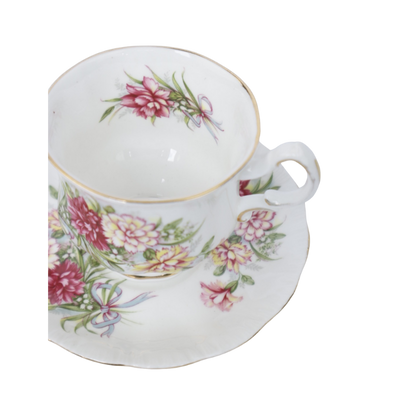 Een wit porseleinen theekopje met bijpassend schoteltje, versierd met roze, gele en rode bloemen op een witte achtergrond.