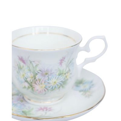 Porseleinen theekopje met schoteltje, versierd met delicate pastelkleurige bloemen en afgewerkt met goudkleurige randjes.