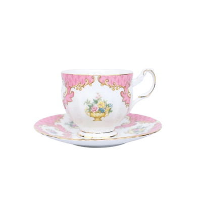 Een porseleinen theekopje met schoteltje, versierd met roze randen, gouden accenten en een bloemenboeket in het midden.