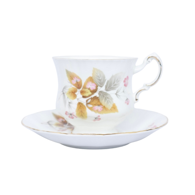 Een wit porseleinen theekopje met schoteltje, versierd met delicate herfstbladeren en kleine roze bloemen.