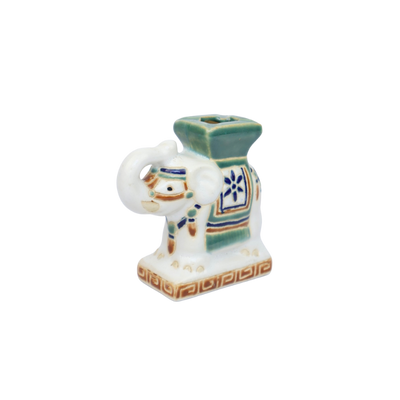 Een kleine, witte keramische olifant met groene accenten, een blauw bloemenmotief en een decoratieve voet.