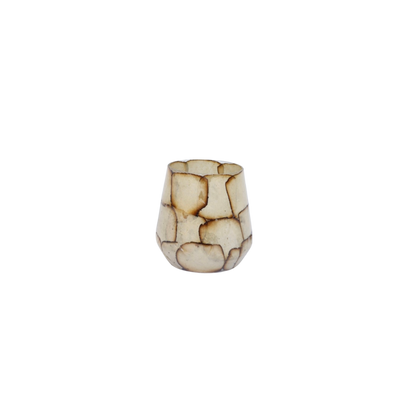 Een cilindervormige kaarsenhouder gemaakt van overlappende, doorschijnende, beige en gebroken witte schelpstukjes.