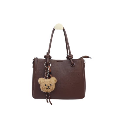 Een donkerbruine leren handtas met twee handvatten en een bungelende pluche teddybeer als bedeltje.