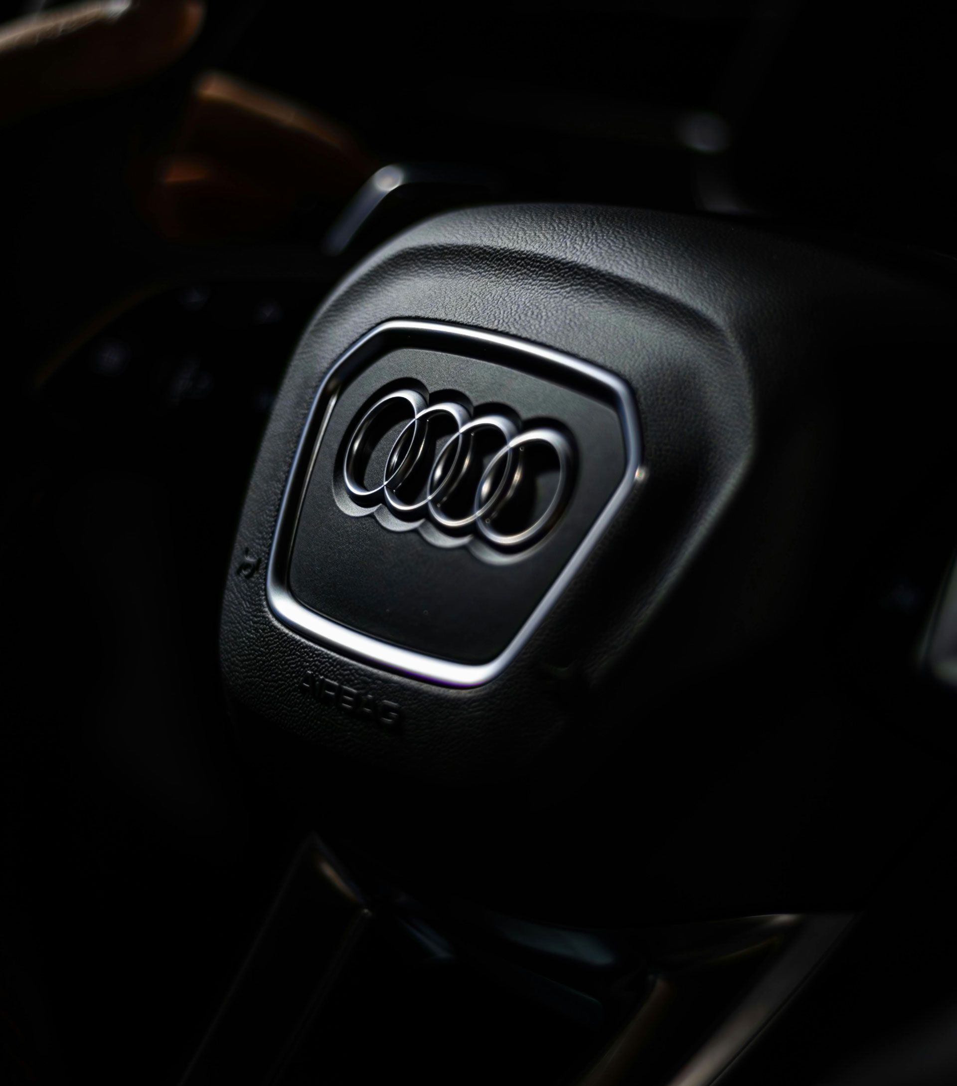 Audi steering wheel center with chrome four-ring logo on black leather