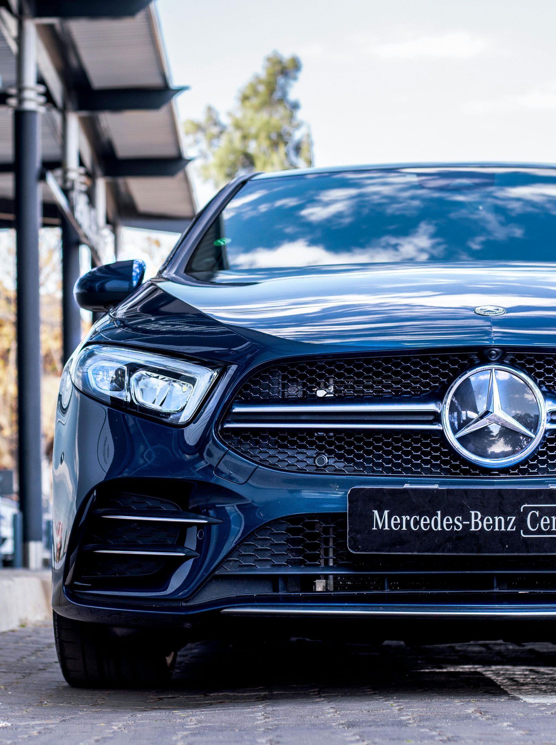 Front view of a black Mercedes-Benz sedan parked outdoors on a sunny day