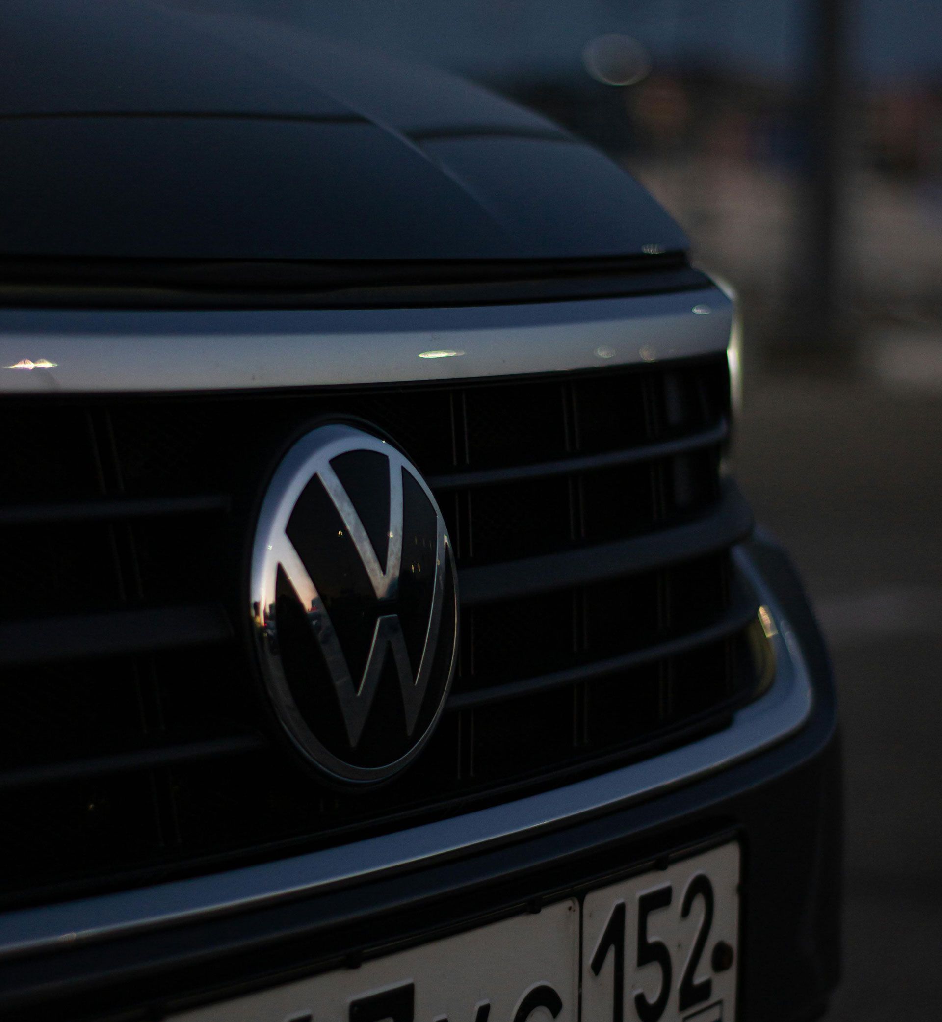 Close-up of a Volkswagen grille and emblem on a dark car, with a partially visible license plate.