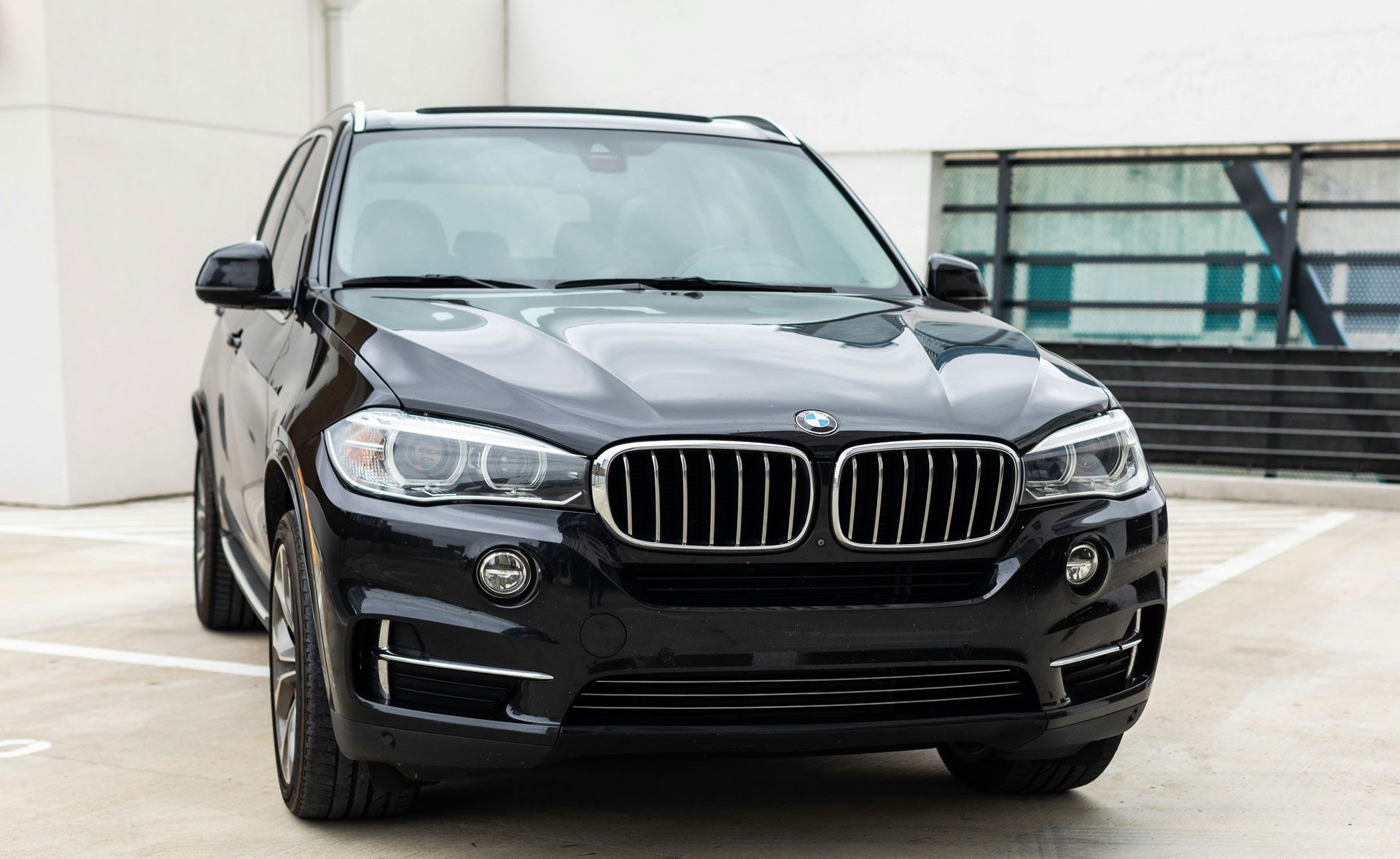 Black BMW SUV parked on a rooftop, front view with city buildings in the background