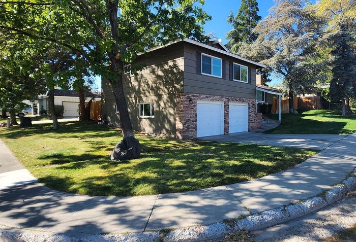 A house with two garages and a sidewalk in front of it