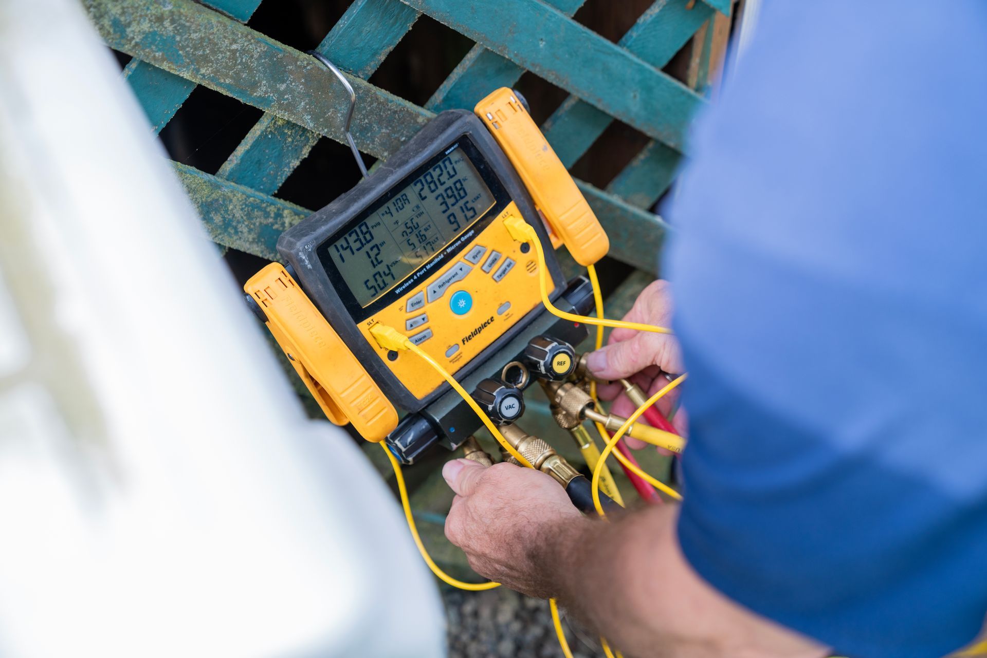 The Clean Air Act Technician is using a yellow and black device to measure air pressure.